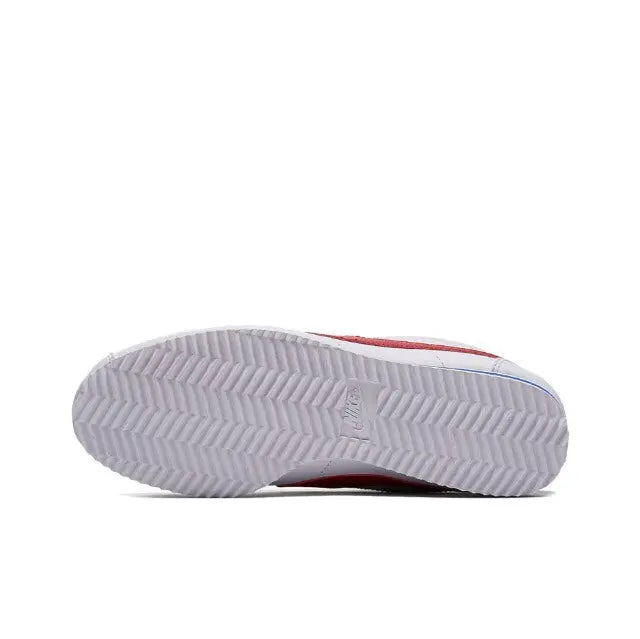 White Nike Cortez sneakers outsole view with textured tread and blue/red accents