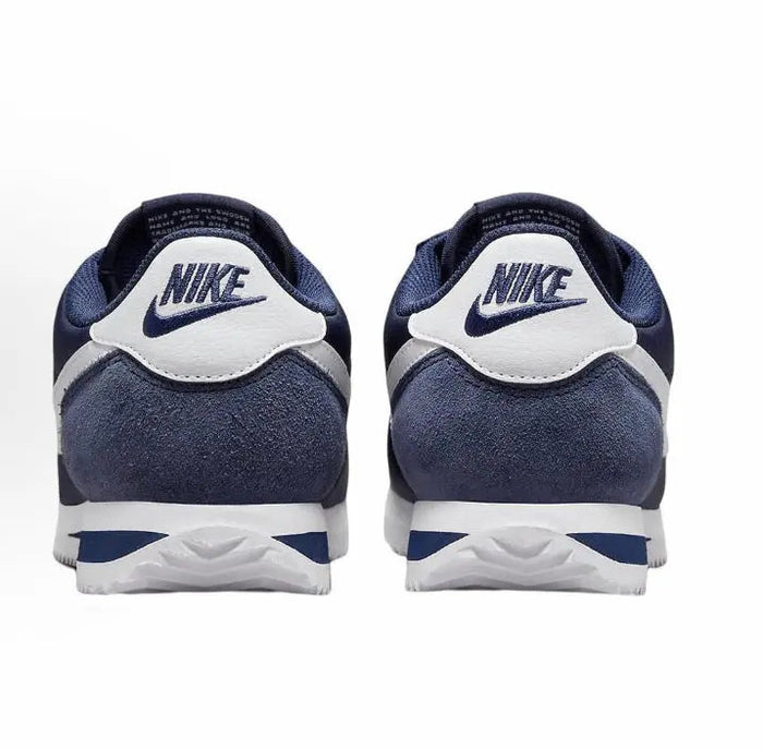 Back view of dark blue sneakers with white heel tabs and blue-striped soles