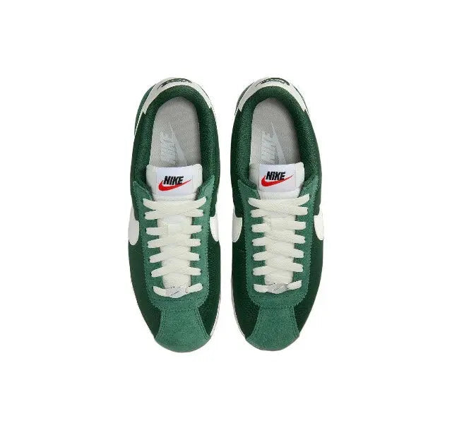 Nike Cortez sneakers with green suede uppers, white laces, and Nike tongue tag.