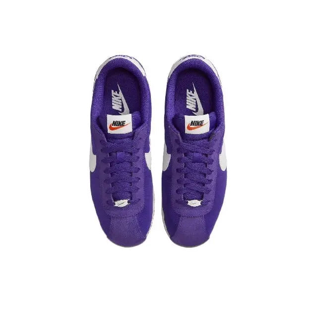 Pair of purple low-top sneakers with white swoosh logos and lace-ups