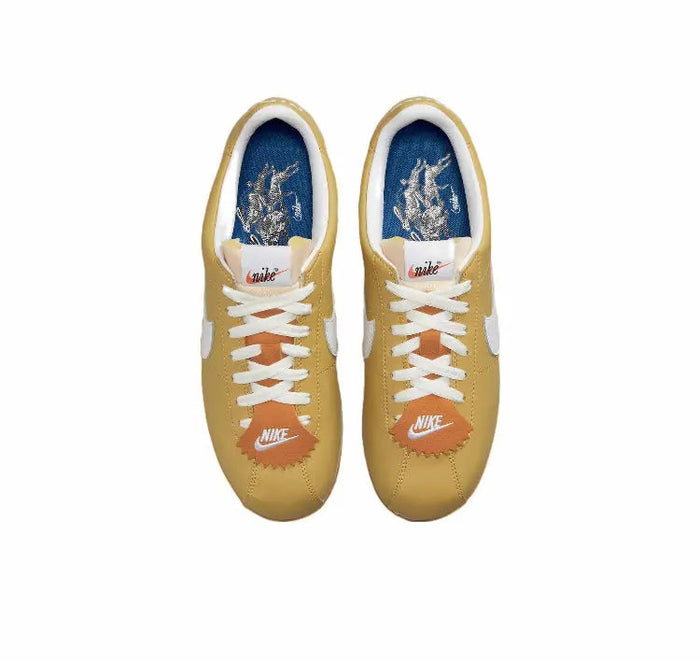Cortez sneakers top view with blue lining, white laces, wheat gold uppers and orange toe