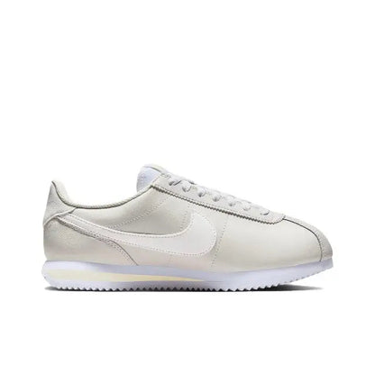 Nike Cortez side view, white low-top sneaker with Swoosh and perforated toe.