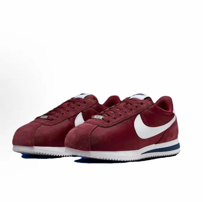 Wine red low-top sneakers with white swooshes and blue-striped midsole, lace-up