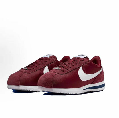 Wine red low-top sneakers with white swooshes and blue-striped midsole, lace-up