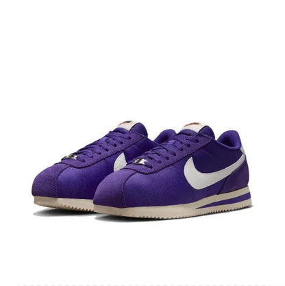 Pair of purple low-top sneakers with white swoosh, lace-up front, and stripes