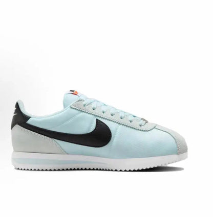 Light blue Cortez sneakers with black Swoosh and orange accent on tongue