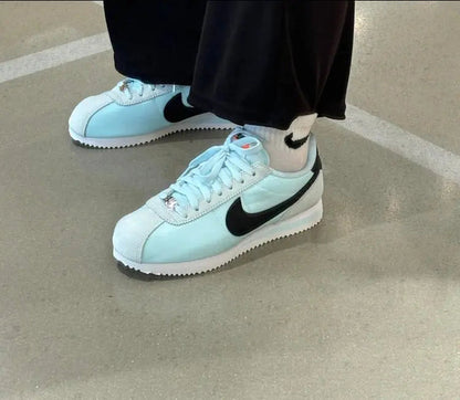Light blue low-top sneakers on pavement, black Swoosh and white sole visible