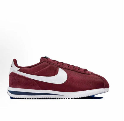 Wine red suede sneakers with white swoosh, lace-up front and blue sole stripe