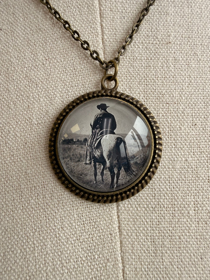 Cowboy glass pendant necklace close-up: round bezel pendant with cowboy on horseback