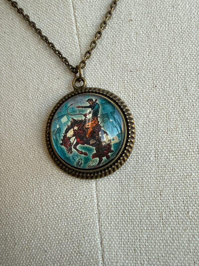 Close-up round glass pendant with bronc scene on bronze chain