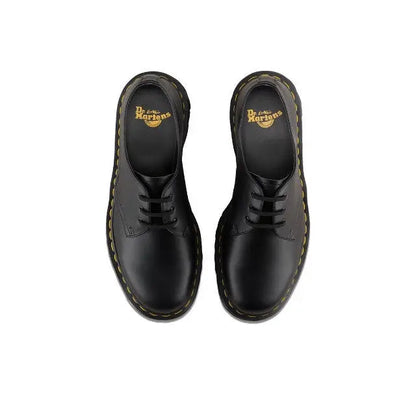 Black lace-up shoe pair with Dr. Martens logo on tongue and yellow welt stitching