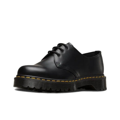 Black lace-up shoe with smooth leather, yellow stitching, and thick treaded sole
