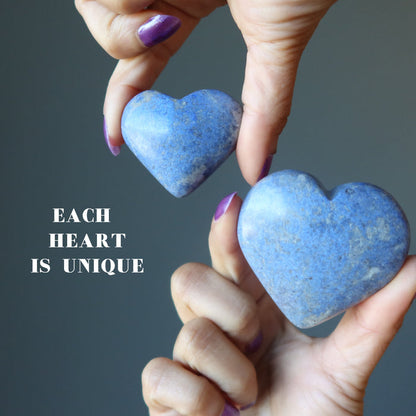 two hands holding dumortierite crystal hearts