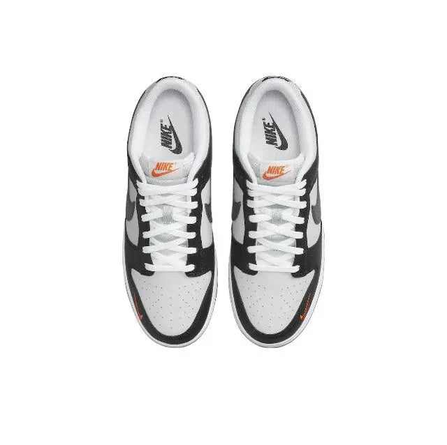 Low-top sneaker pair with black overlays, white panels, and orange swoosh accents