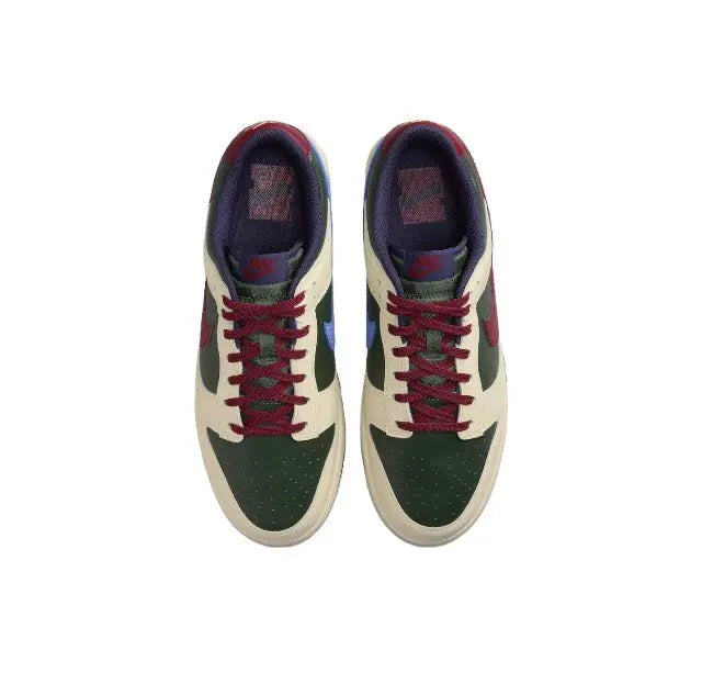 Low-top sneakers front view: cream toe, dark green overlays, red laces, navy lining.