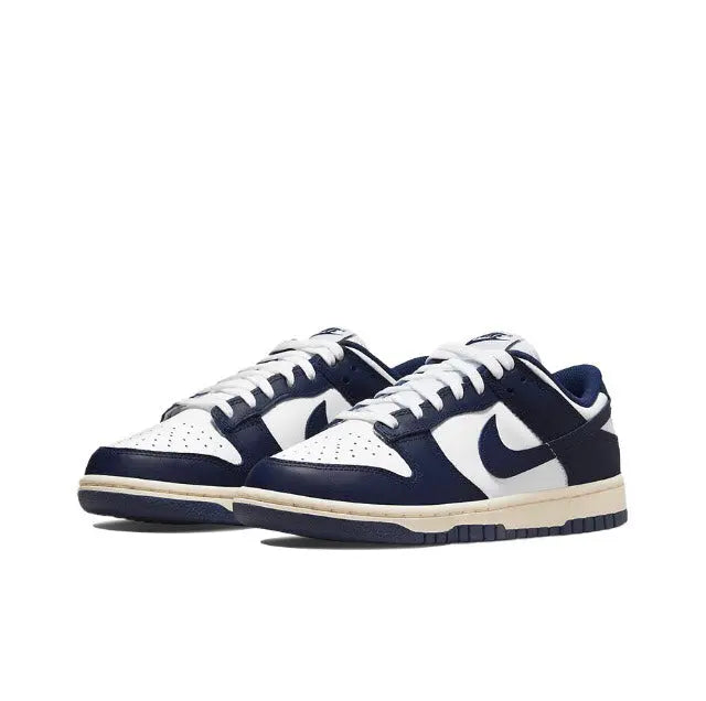Low-top sneakers angled side view in white and navy with cream midsole