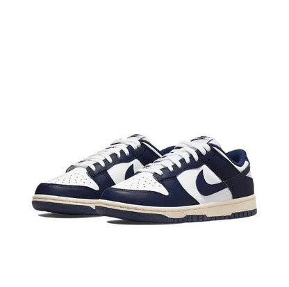 Low-top sneakers angled side view in white and navy with cream midsole