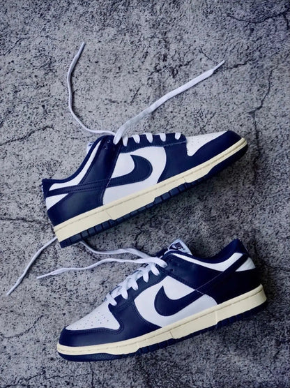Pair of low-top sneakers with white laces, navy uppers, and cream soles