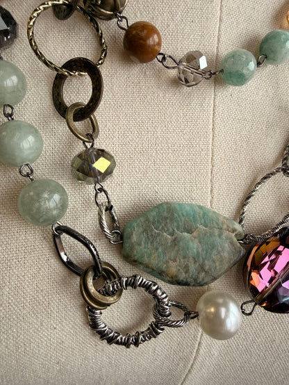 Layered necklace close-up with blue-green and pearl-like beads, faceted amber stone, silver links