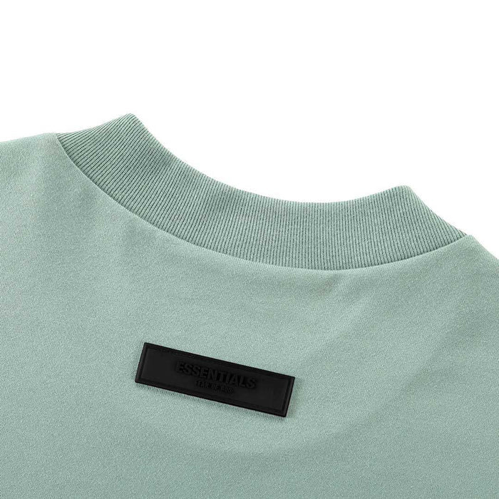 Light blue crew-neck T-shirt with black Essentials patch at chest