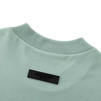 Light blue crew-neck T-shirt with black Essentials patch at chest