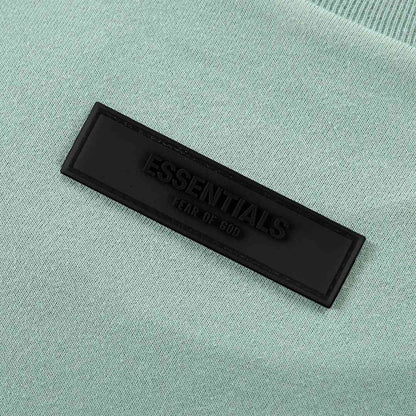 Light blue T-shirt with rectangular black Essentials brand patch