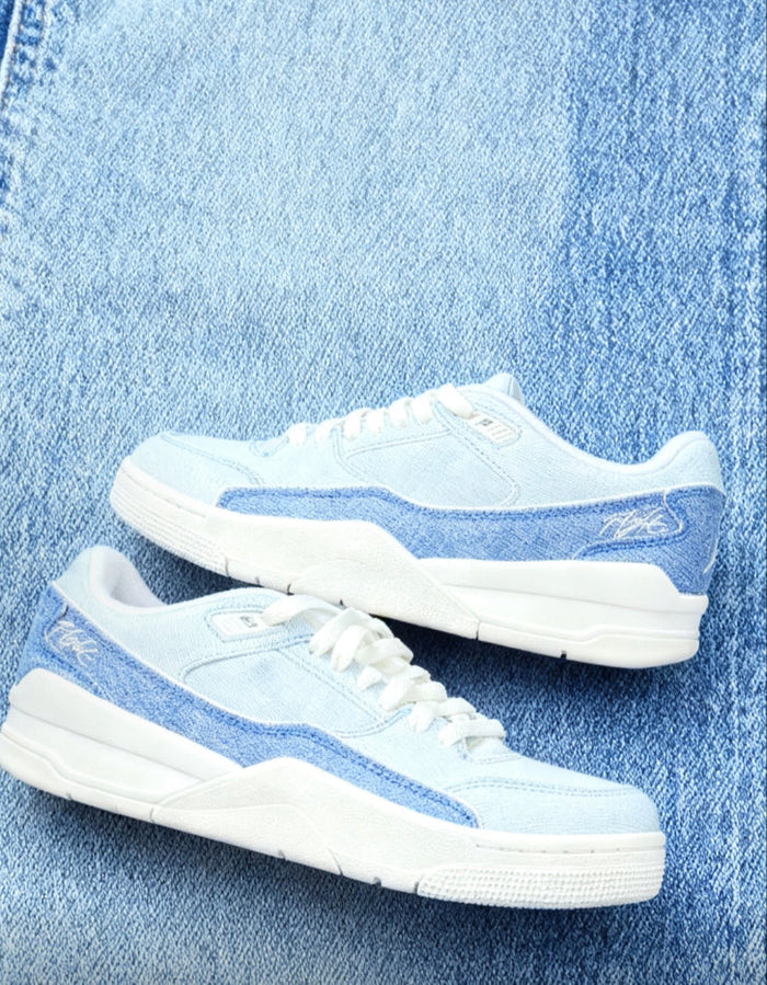 White and light blue low-top sneakers with laces and blue side stripe on denim.