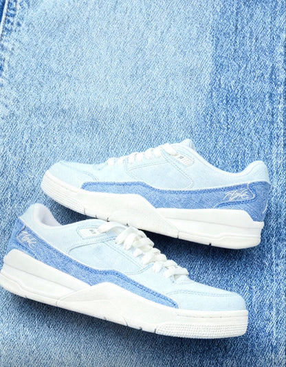 White and light blue low-top sneakers with laces and blue side stripe on denim.