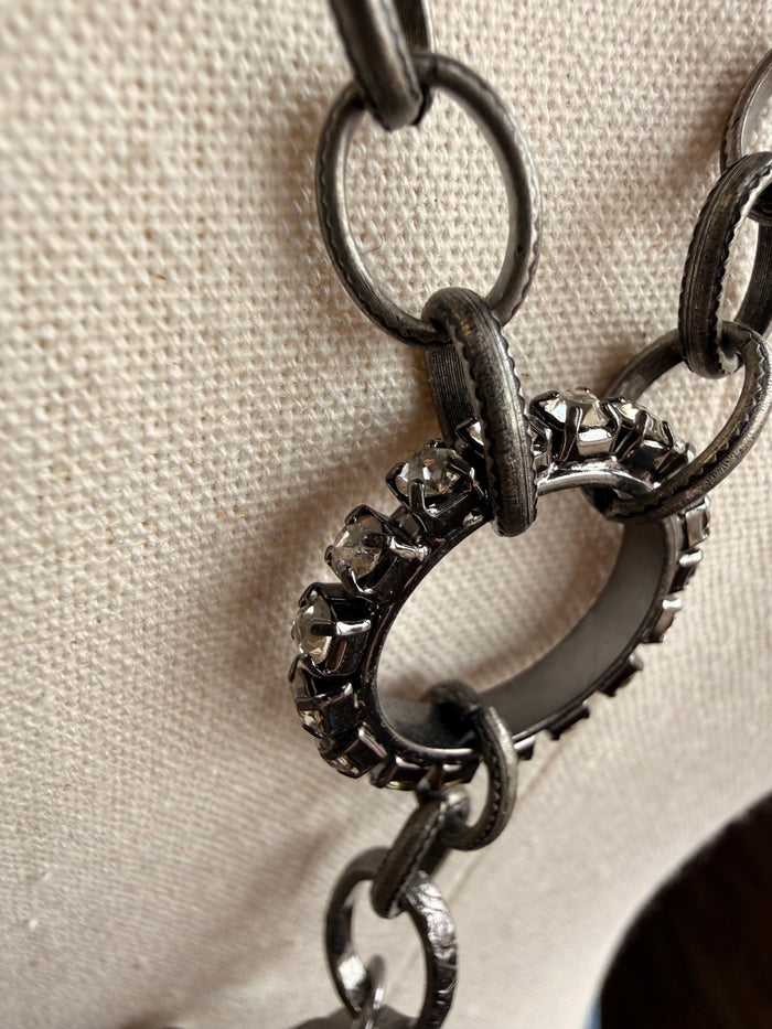 Floral crystal pendant necklace with dark metal chain, close-up of link and stone charm