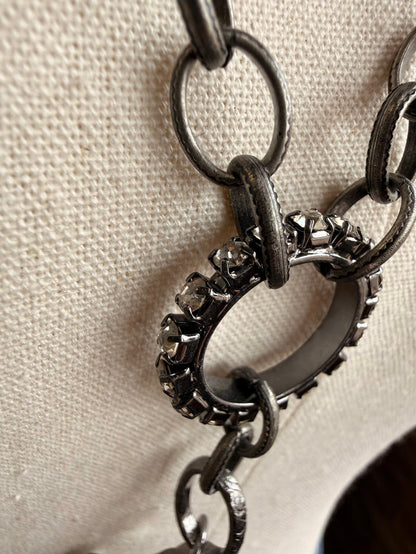Floral crystal pendant necklace with dark metal chain, close-up of link and stone charm
