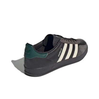 Low-top sneakers with dark leather, cream side stripes, and green collar tab