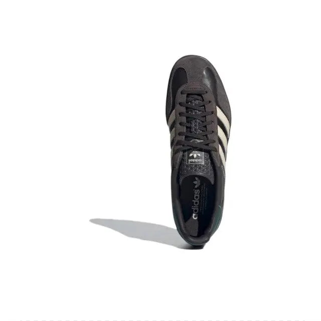 Low-top sneakers with dark upper, black laces, cream side stripes, and padded collar