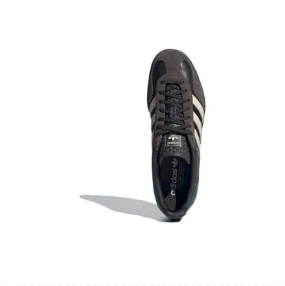 Low-top sneakers with dark upper, black laces, cream side stripes, and padded collar