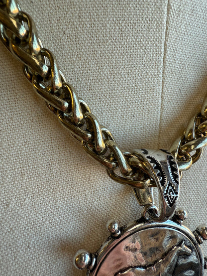 Close-up of horse coin medallion pendant on gold-tone chain with ornate clasp bail