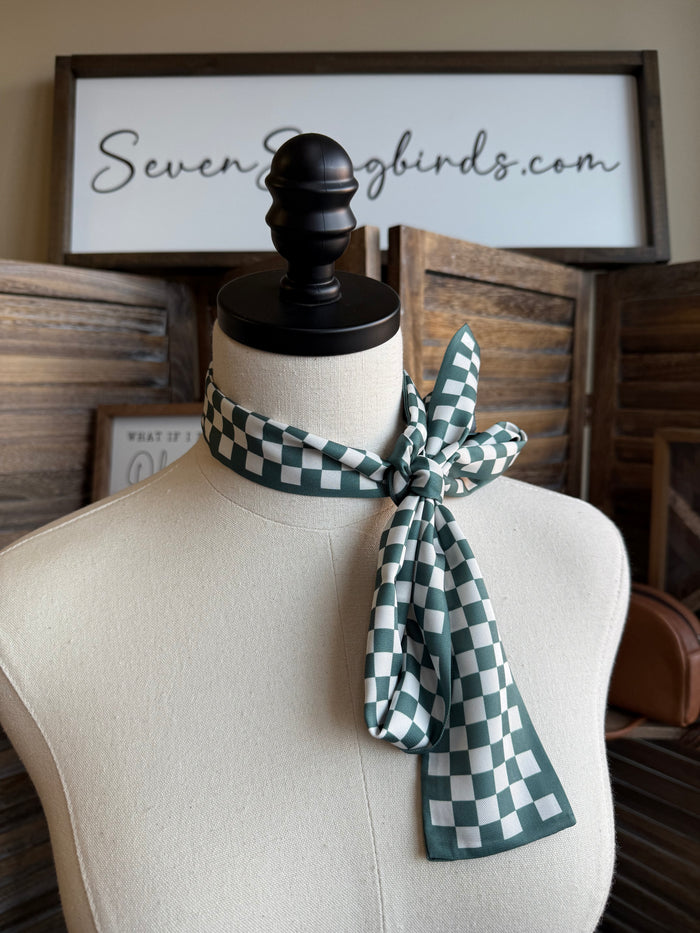 Green and white checked twilly scarf tied in a knot bow at the neck