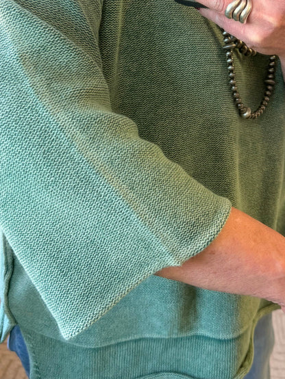 Green knit sweater sleeve with 3/4 length cuff and round neckline