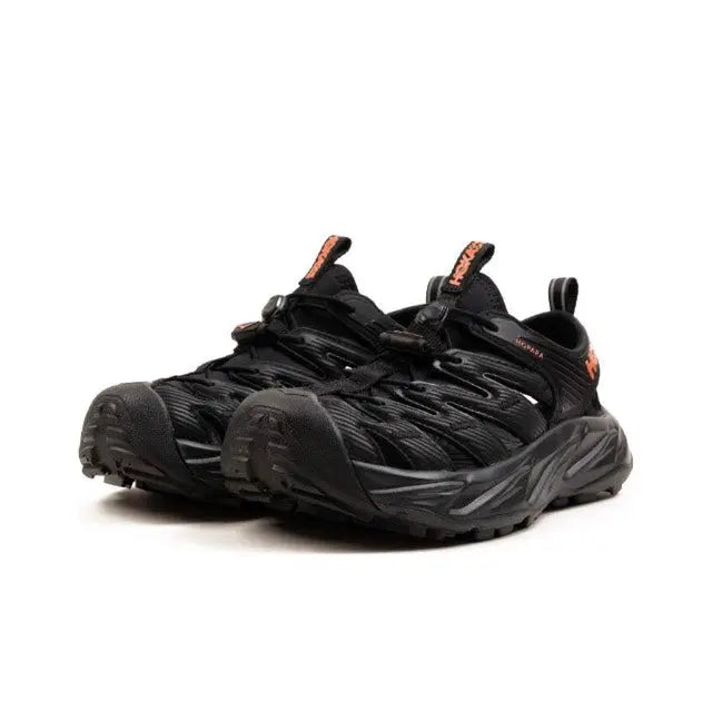 Trail shoe in black with textured upper and chunky rubber sole, lace-up
