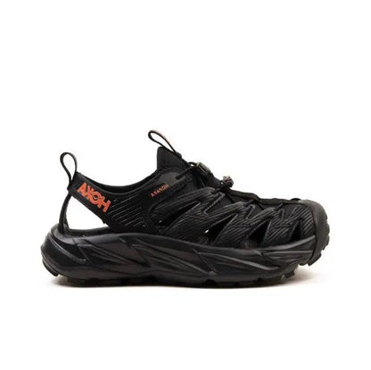 Trail shoe side profile, black upper with orange logo accents and thick sole