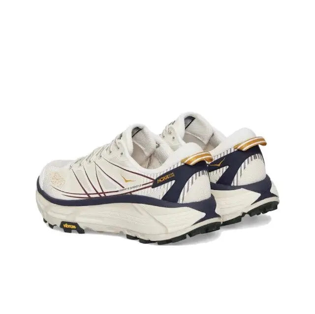 Trail running shoe side view in light cream with navy stripes and gold heel pull