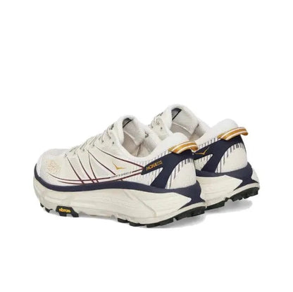 Trail running shoe side view in light cream with navy stripes and gold heel pull