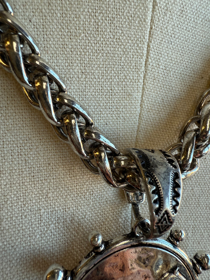 Round horse coin pendant with ornate bail and chunky link chain, close-up