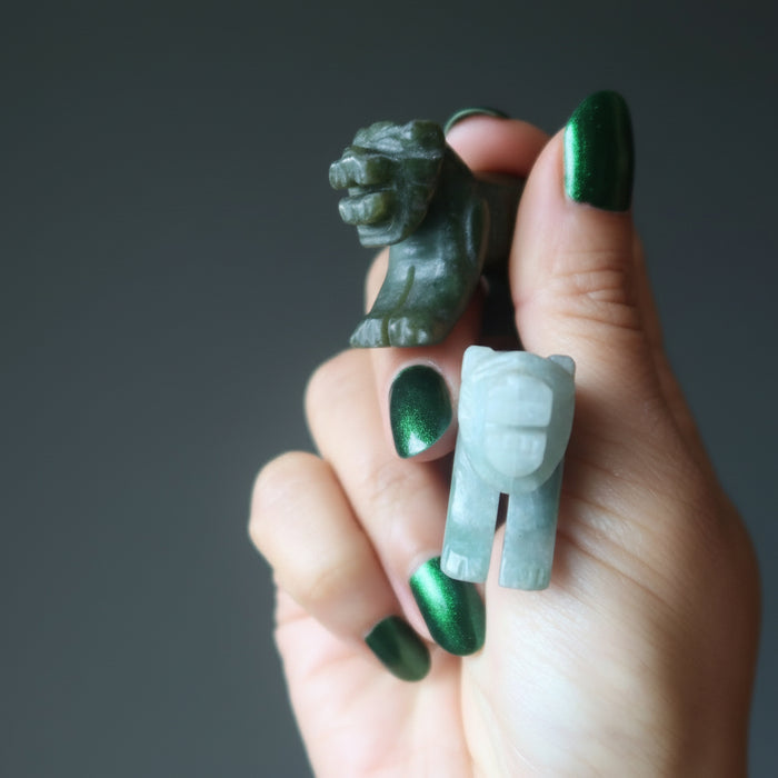 hand holding two green jade tiger carvings