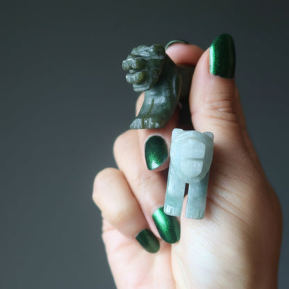 hand holding two green jade tiger carvings
