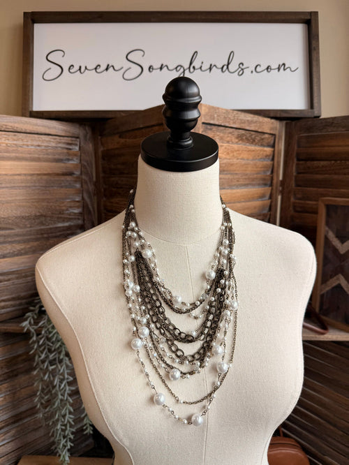 Layered pearl and chain necklace on mannequin, multiple pearl strands with dark chains