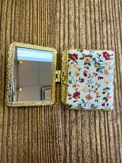 White floral mirror compact with hinged case and round mirror, gold-tone frame