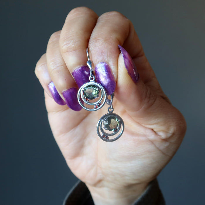 hand holding moldavite garnet earrings