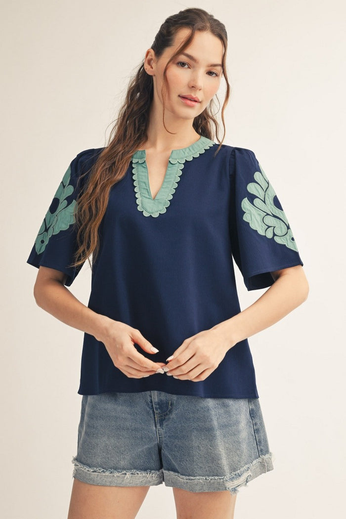 Navy shirt with green scalloped neckline and short puff sleeves
