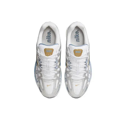 White sneakers with laced uppers and Nike tongue label, gold heel emblem