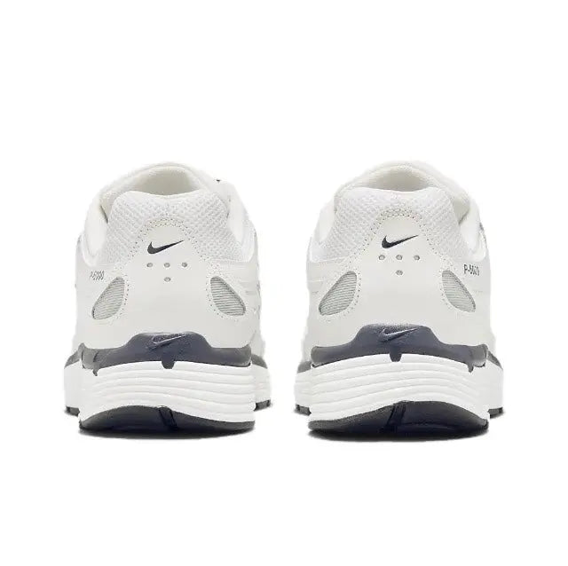 White Nike running sneakers, rear view with blue heel accents and ribbed sole