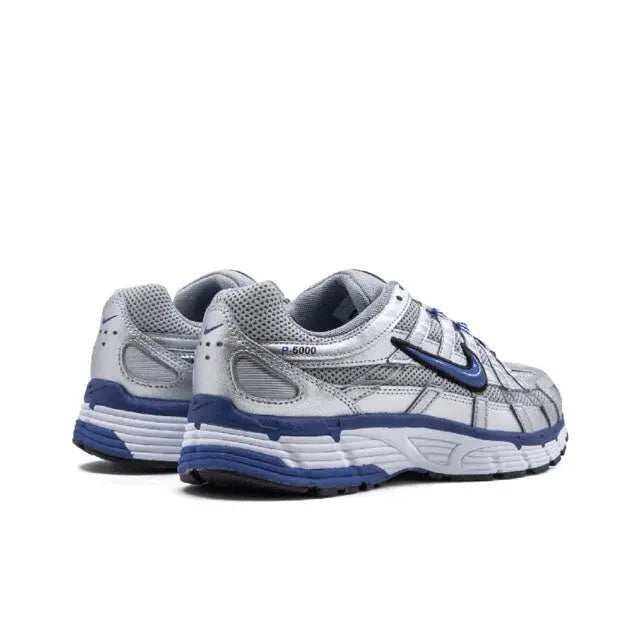 Nike running shoe in silver with blue heel and Swoosh, cushioned foam sole.
